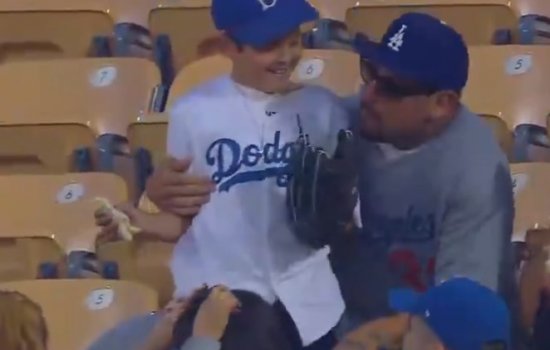 Мальчик поймал на трибуне бейсбольный мяч с сэндвичем в другой руке